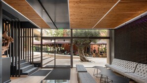 Un interior moderno con zona de estar, una escalera y vistas al patio exterior.