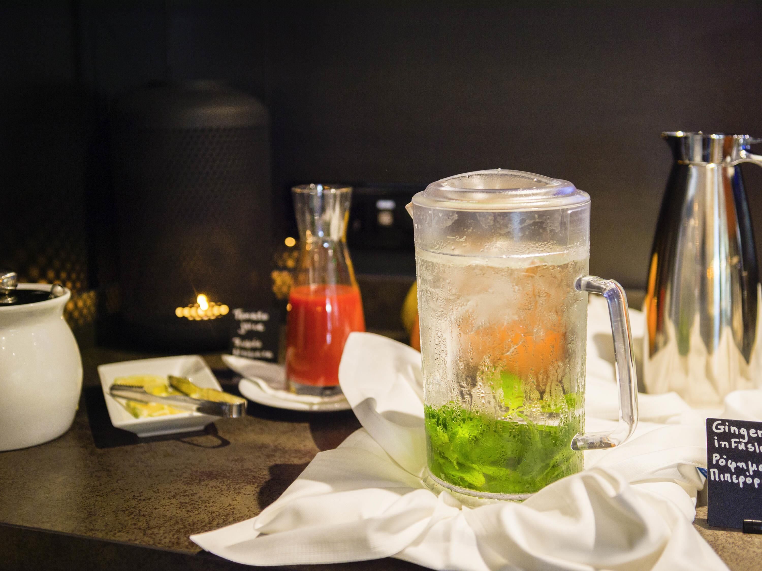 A table with a pitcher of iced tea, a glass of water, and a bottle of red sauce.