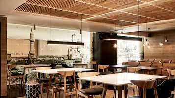 A modern restaurant with wooden tables and chairs, a wooden ceiling design, and a view of a building in the background.