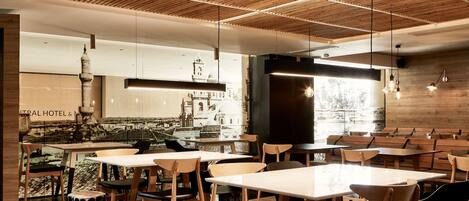 A modern restaurant with wooden tables and chairs, a wooden ceiling design, and a view of a building in the background.