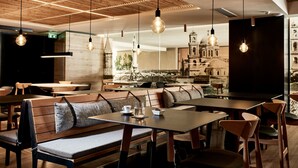 Un restaurante con mobiliario de madera, lámparas colgantes y vistas a un edificio histórico.