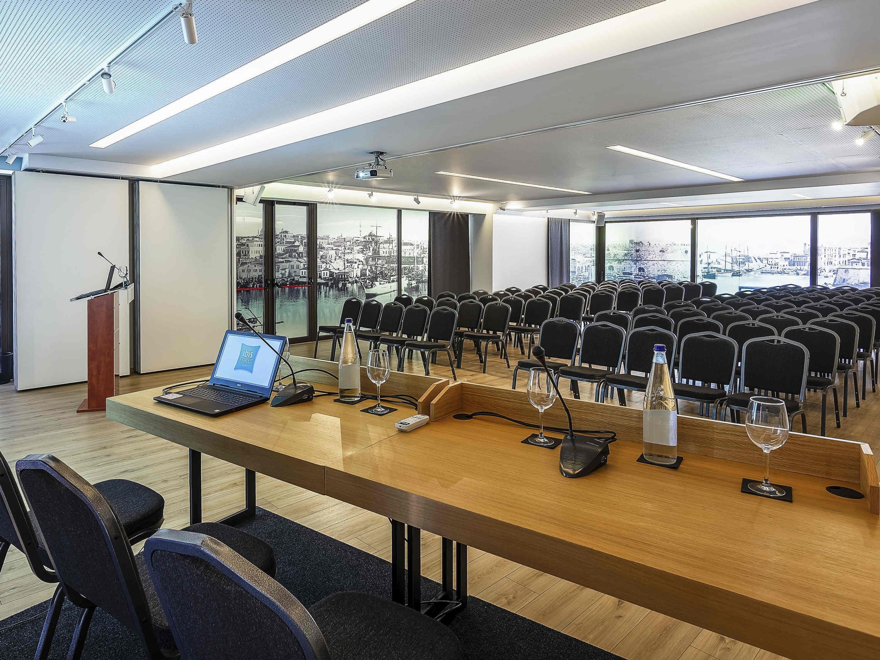 A conference room with rows of chairs, a podium, a laptop, and a projector.
