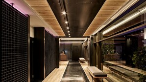 Un interior moderno con un pasillo central, suelo de madera y un banco a lo largo de la pared derecha.