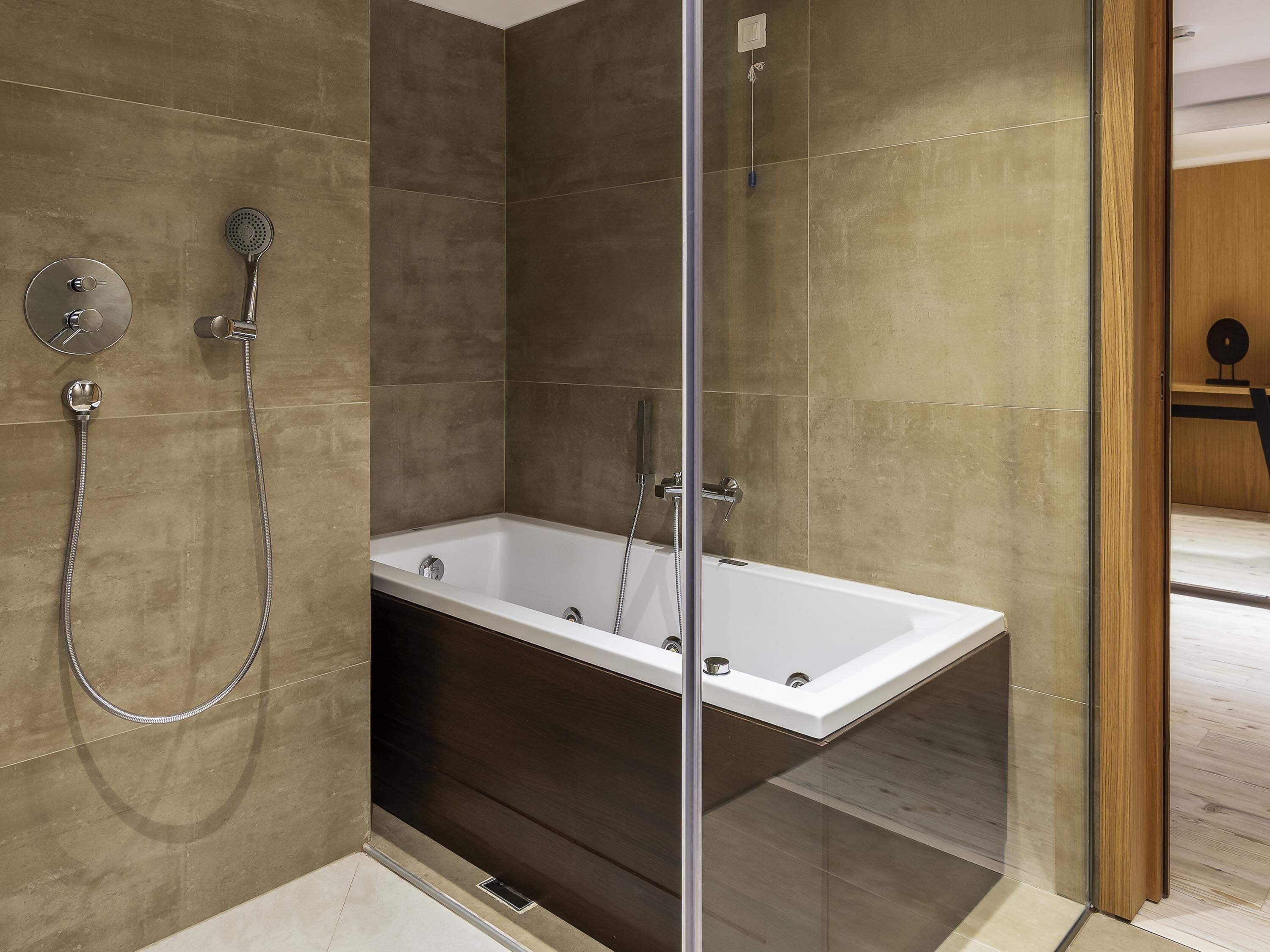 Un baño moderno con ducha de vidrio, bañera independiente y grifo empotrado.