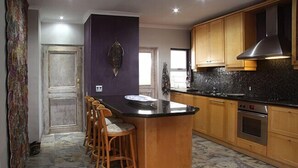 Una cocina con isla central, armarios de madera, extractor de acero inoxidable y salpicadero de azulejos.