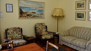 A room with a wooden table, two floral armchairs, a beige sofa, and a floor lamp. - Paul Kruger 63 (Robertson)