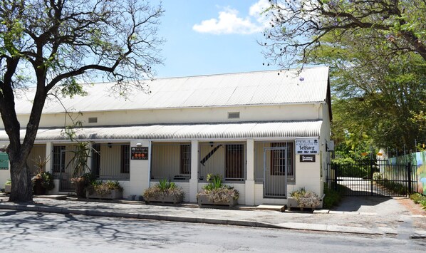 A two-story building with a corrugated metal roof, multiple windows, and a signboard advertising a self-catering cottage. - Paul Kruger 63 (Robertson)