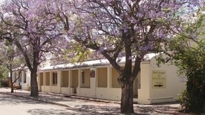 A row of single-story buildings with a sign indicating a parking area. - Paul Kruger 63 (Robertson)