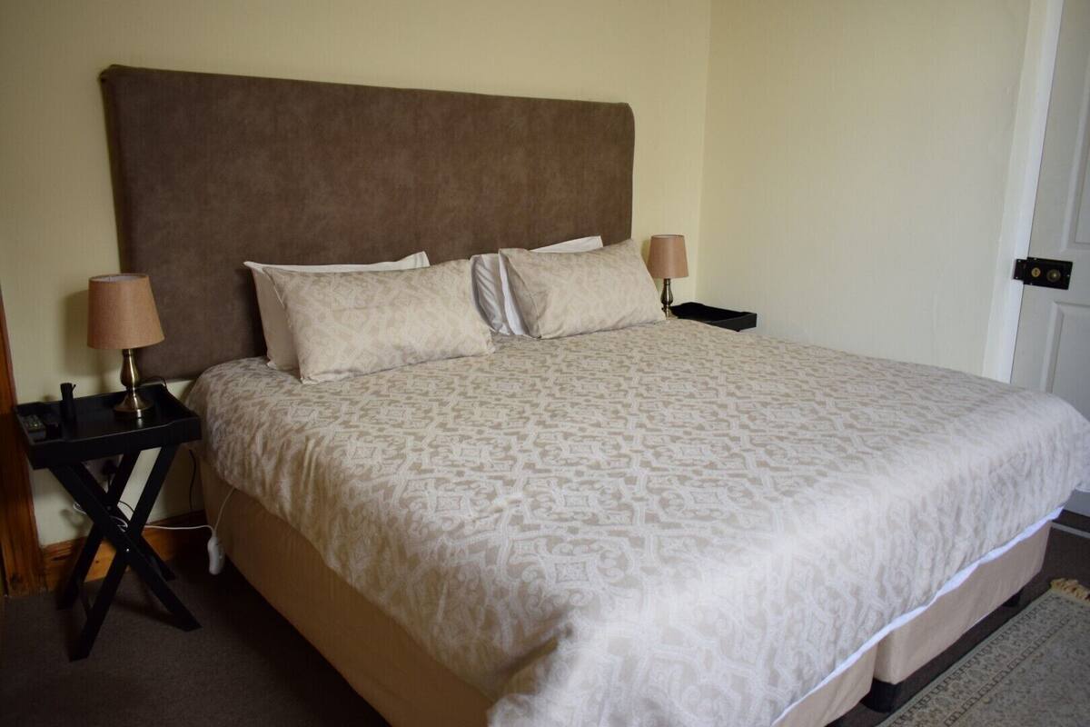 A neatly made bed with a patterned bedspread, two bedside lamps, and a dark-colored nightstand.
