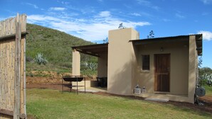 A small, single-story building with a patio area, a barbecue grill, and a satellite dish. - Die Ou Huis (Ashton)