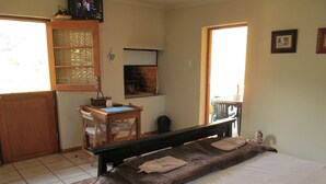 A bedroom with a bed, a desk, and a chair. There is a window and a door. - Die Ou Huis (Ashton)