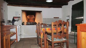 A kitchen with a wood stove, wooden chairs, and a tiled floor. - Die Ou Huis (Ashton)