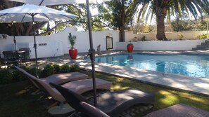 A pool area with lounge chairs, umbrellas, and potted plants. - Slaley Country House (Stellenbosch)