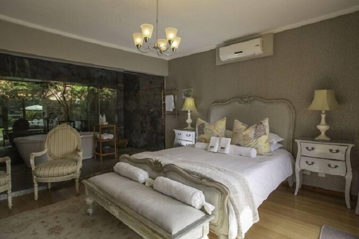 A bedroom with a large bed, bedside tables, a chair, and a bench.