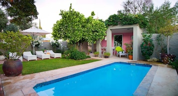 Una piscina al aire libre, sombrillas, sillones reclinables de piscina