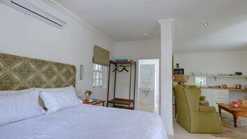 A bedroom with a bed, a wooden bench, a chair, a small table, and a window.