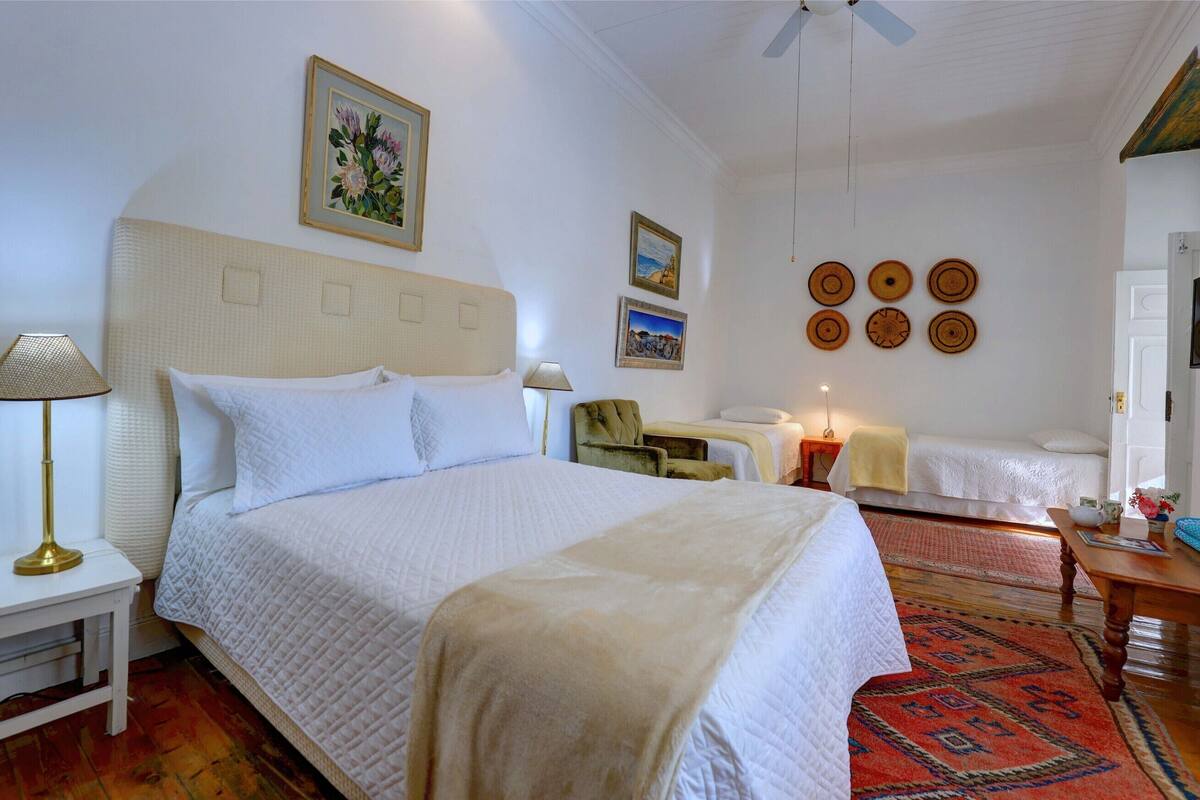 A hotel room with a large bed, two bedside tables, a chair, a small table, and a TV.