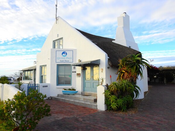 A white building with a blue door and a sign reading "Gilcrest Place Guest House."