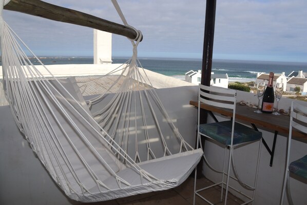 A hammock chair, a bar area with two stools, and a view of the ocean. - Gilcrest Place (Paternoster)
