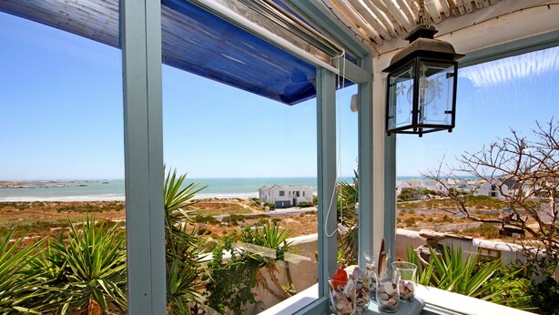 A balcony with a view of the sea and a coastal town. - Gilcrest Place (Paternoster)