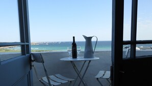 A balcony with a table, two chairs, a wine bottle, and a pitcher.