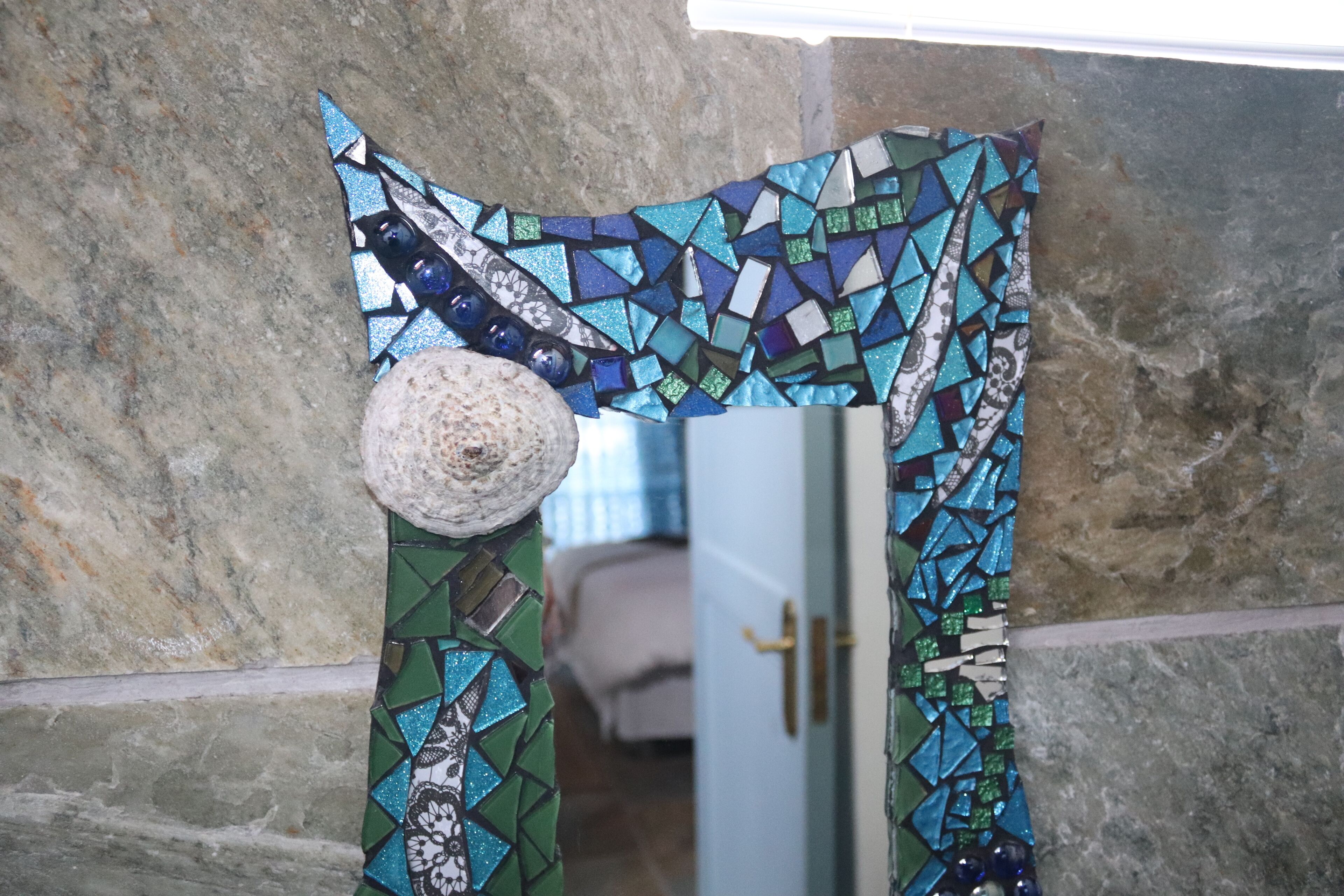 Un umbral de mosaico con una pared de piedra y una puerta.