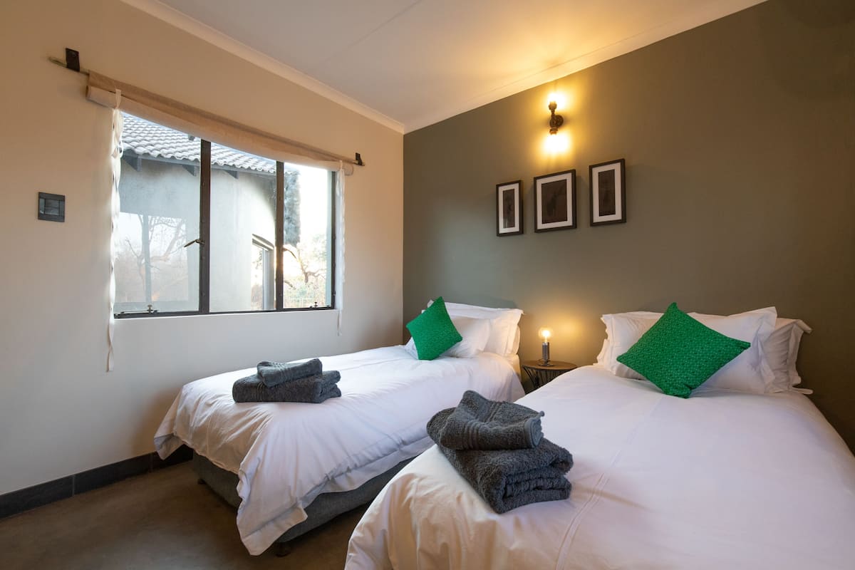 Habitación de hotel con dos camas, una ventana con vistas y luces fijadas a la pared.