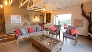 Uma sala de estar aconchegante com uma mesa de centro de madeira, um sofá cinza com almofadas coloridas e uma cadeira de madeira.