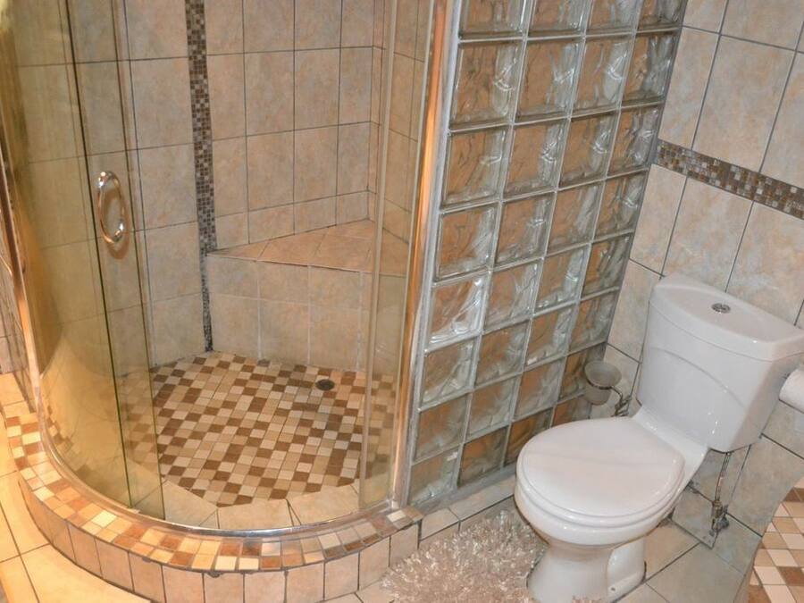 Une douche avec une porte en verre et des carreaux de sol à motifs carrés.