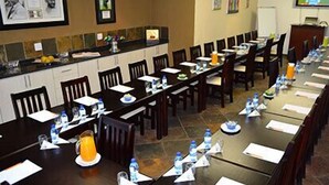 A conference room with long tables, chairs, water bottles, and papers. - Ikhanda Guesthouse (Mashishing)