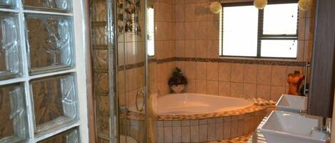 Un baño con cabina de ducha de vidrio, una bañera independiente y un tocador con lavamanos.
