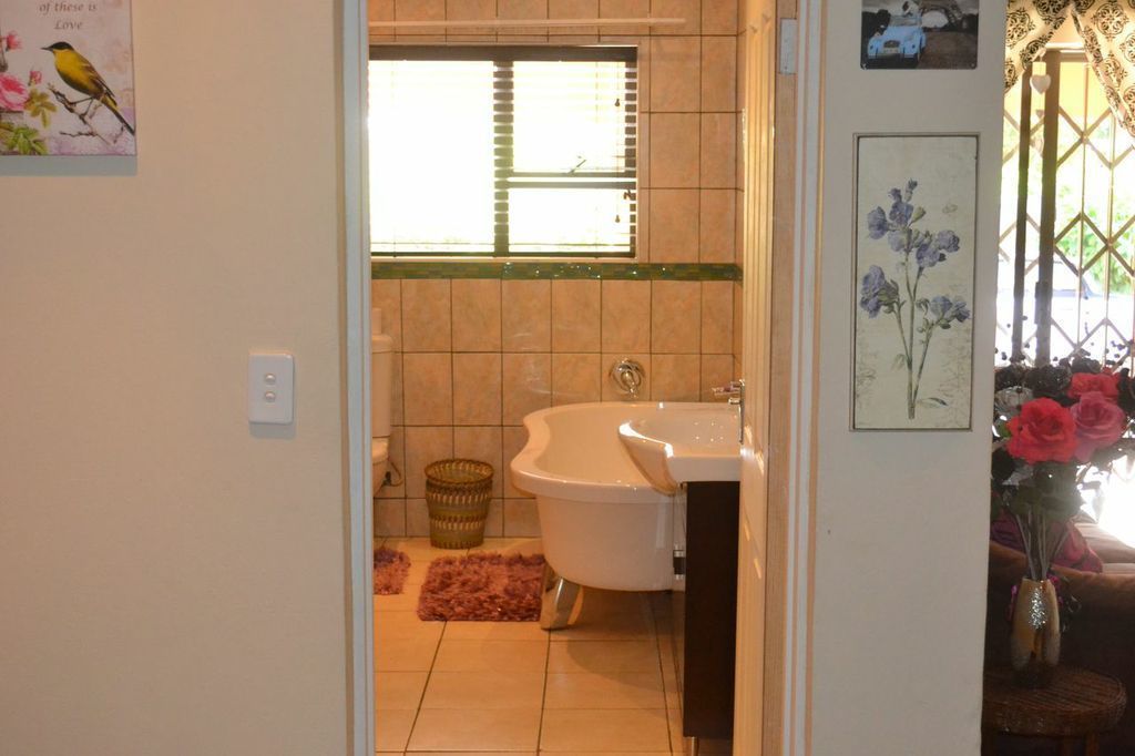 A bathroom with a bathtub, a sink, and a window with blinds.