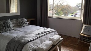 A bedroom with a large bed, a window with a view of the outside, and an air conditioning unit on the wall. - Stell On Air (Stellenbosch)
