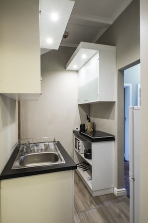 A compact kitchen with a sink, countertop, and cabinets. - Faith, Hope & Love (Gqeberha (Port Elizabeth))