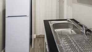 A modern kitchen with a white refrigerator, stainless steel sink, and black countertop. - Faith, Hope & Love (Gqeberha (Port Elizabeth))