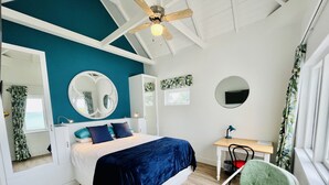 A bedroom with a bed, a desk, a chair, a ceiling fan, and a window with curtains. - Sunny Cove Manor (Cape Town)