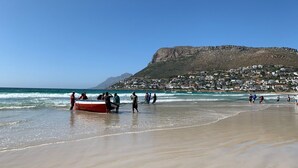 A beach with a boat, people, and a mountain in the background. - Sunny Cove Manor (Cape Town)