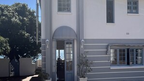 A two-story building with a symmetrical facade, a central entrance with a semi-circular arch, and a small balcony with a railing. - Sunny Cove Manor (Cape Town)