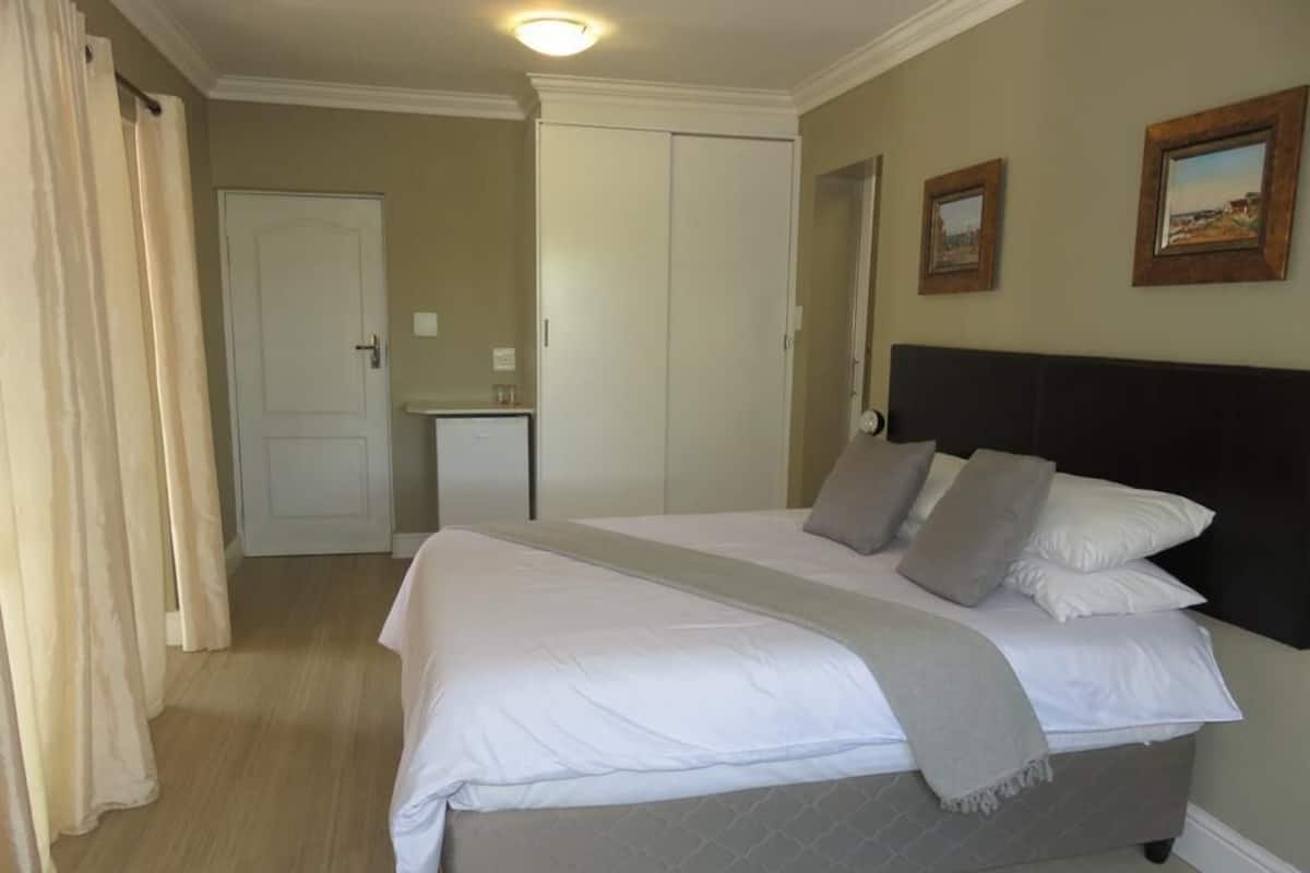 A bedroom with a bed, a nightstand, a dresser, and a door.