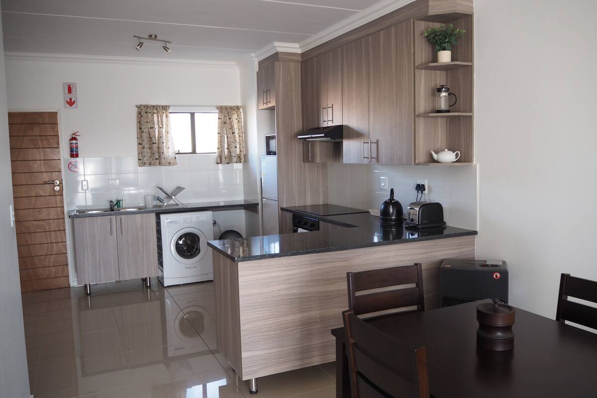 Una cocina moderna con lavadora integrada, microondas y cafetera.