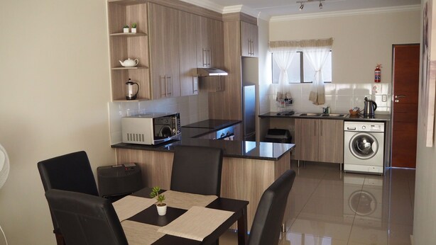 A modern kitchen with wooden cabinets, a built-in microwave, and a washing machine.