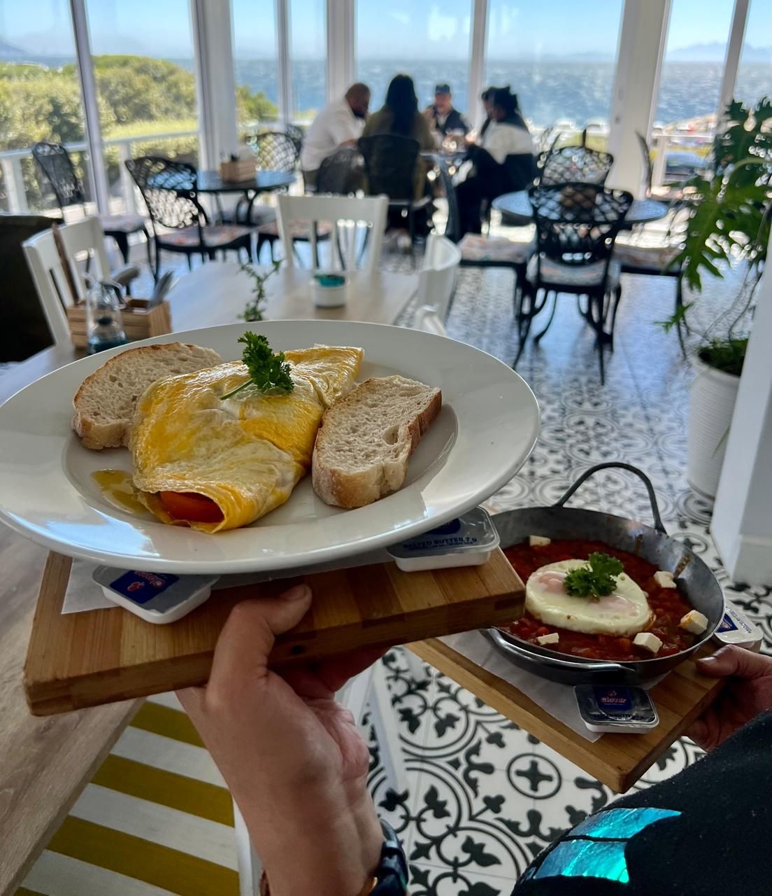 A dining table with a plate of food, a bowl of sauce, and a tray with bread.