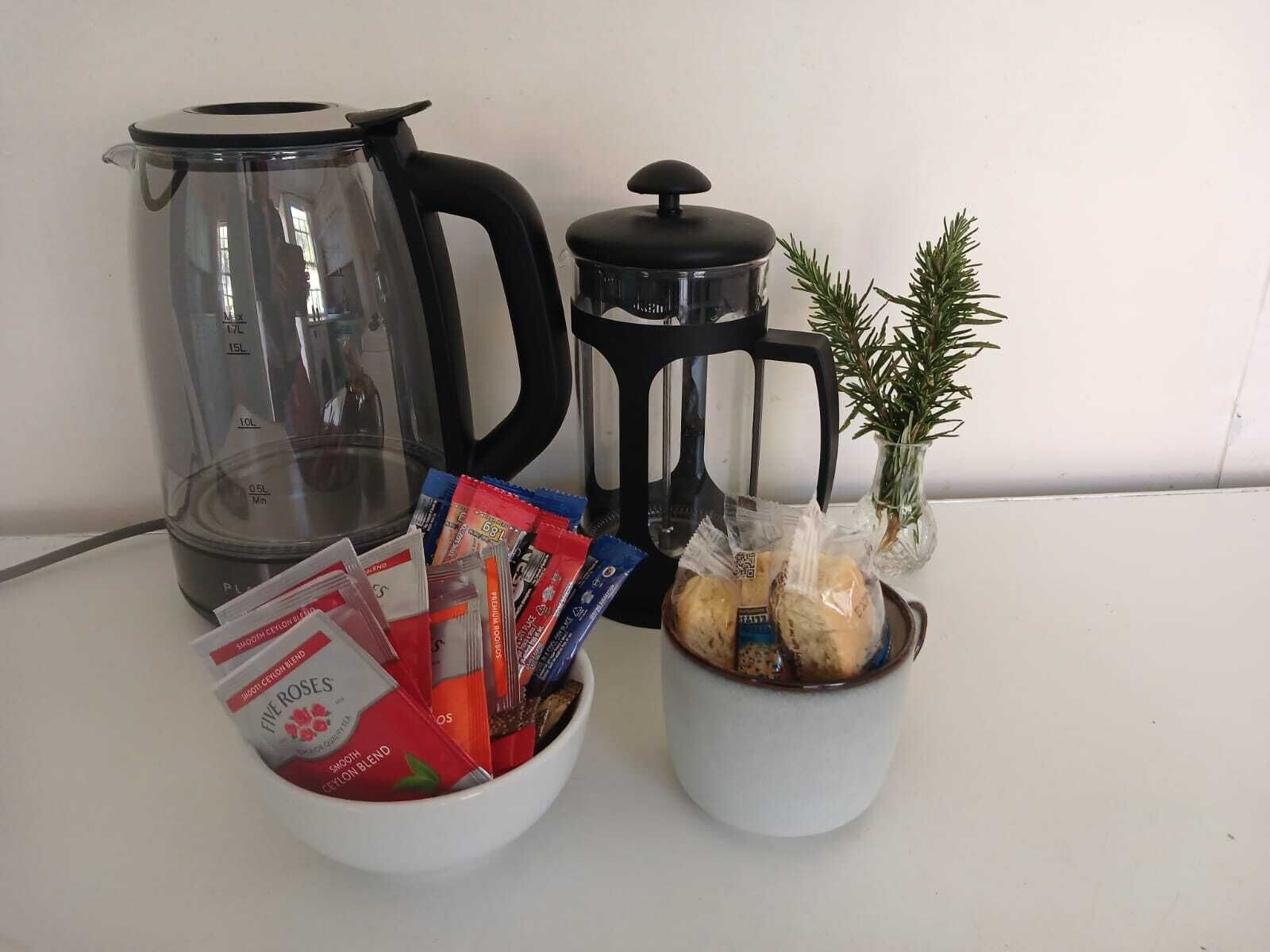 Keittiön työtasolla on kahvinkeitin, vedenkeitin, kattila, muki sekä kulho, jossa on ruoka-aineita ja paketteja.