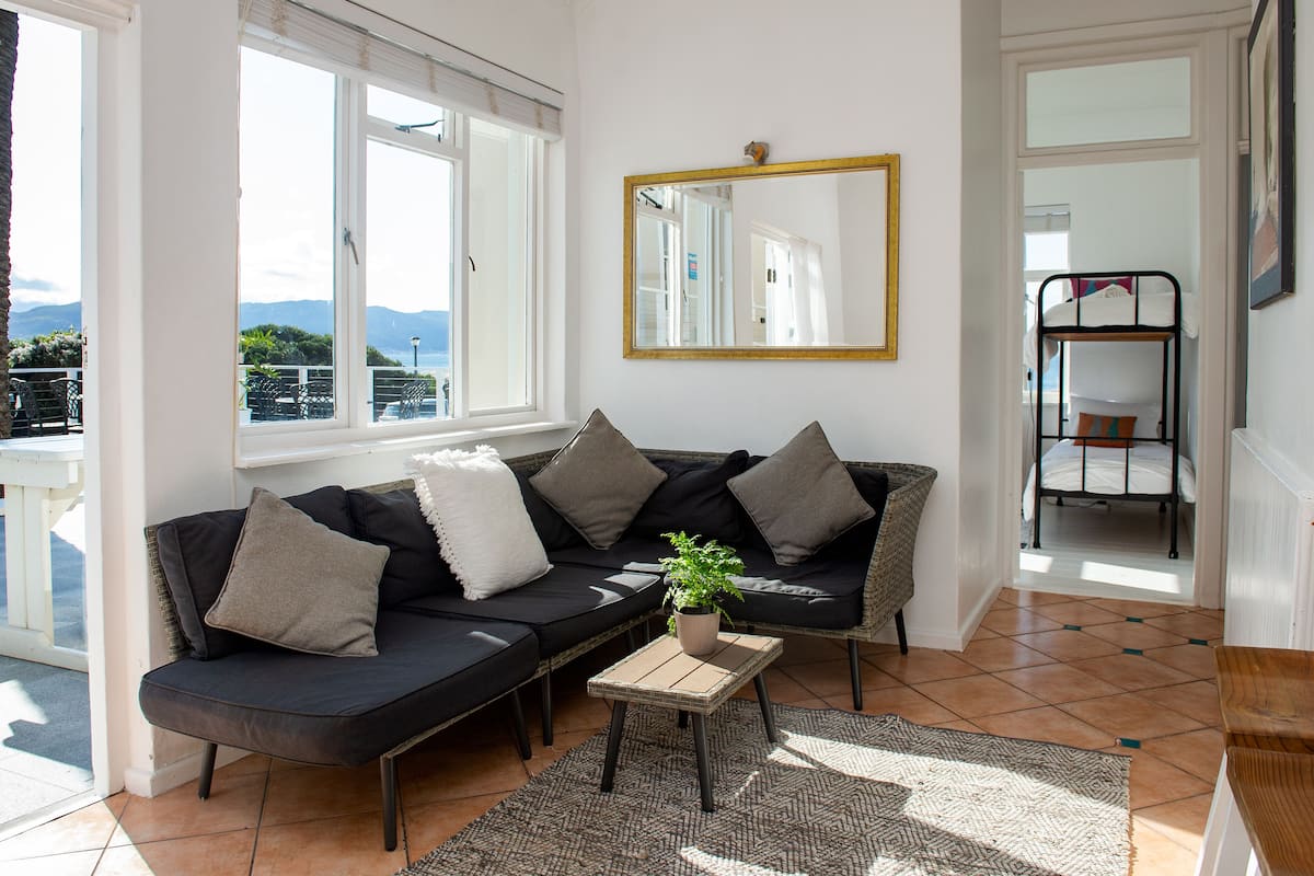 Ein Wohnzimmer mit einer Couch, einem kleinen Tisch, einer Topfpflanze und einem Spiegel an der Wand.