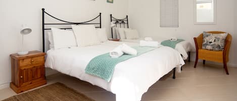 A bedroom with a bed, a nightstand, a chair, and a window.