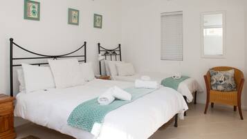 Une chambre avec deux lits, une chaise et des œuvres d’art accrochées au mur.