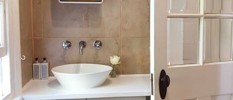A bathroom with a white sink, two faucets, a mirror, and a door with glass panels.