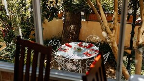 A round table with a white tablecloth and red napkins, set outdoors with metal chairs. - Carmichael Guesthouse (Rosebank)