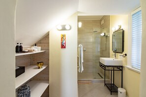 A modern bathroom with a shower, sink, and shelves with toiletries. - Carmichael Guesthouse (Rosebank)