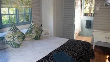 A bedroom with a bed, a window, a wardrobe, and a bathroom visible through an open door.